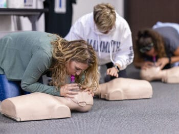 Women practicing CPR on a manikin in a CPR certification class.