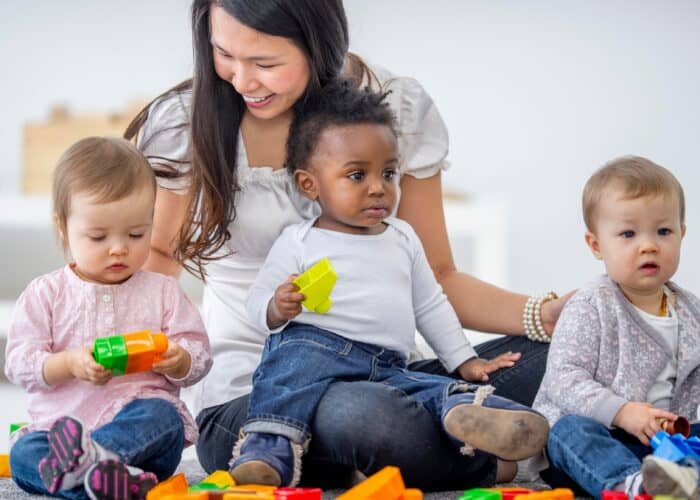 Childcare provider interacts with small children at a day care center. 